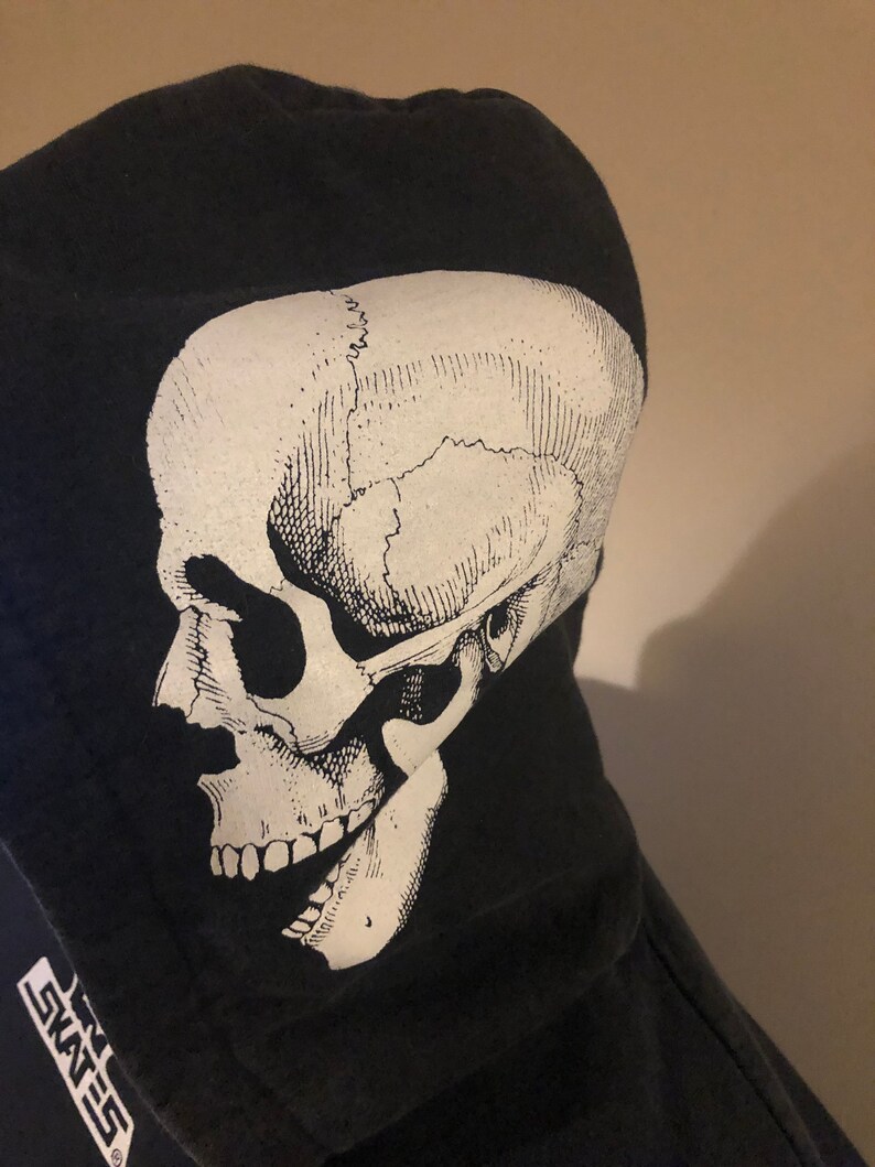 May include: Black hooded sweatshirt with a white skull graphic on the front. The skull is a detailed anatomical illustration. The text "SKATES" is visible on the bottom left corner of the sweatshirt.