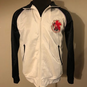 May include: White and black track jacket with a zipper closure. The jacket has a purple stripe on the collar and a red and black embroidered patch on the chest. The patch features a scorpion and the text "Scorpions Wrestling Federation".
