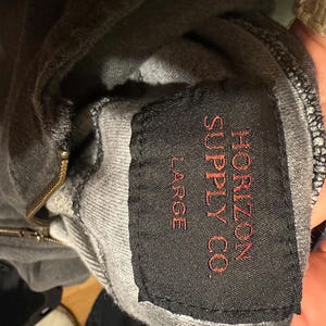 May include: A gray hooded sweatshirt with a black tag that reads "Horizon Supply Co." and "Large" in red lettering.