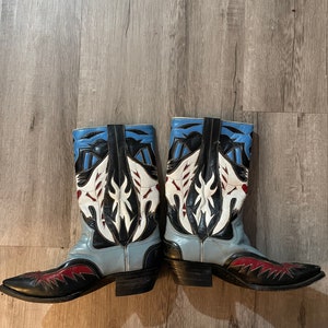 May include: A pair of blue, black, white, and red cowboy boots with intricate designs on the shaft.