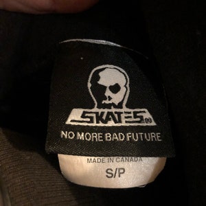 May include: Black and white label with a skull logo and the text "SKATES" and "NO MORE BAD FUTURE". The label also says "MADE IN CANADA" and "S/P".