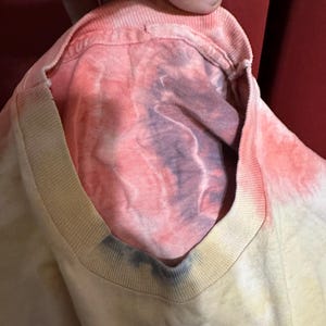 K&ouml;nnte beinhalten: Ein Batik-T-Shirt mit einem verblassten Farbverlauf in Rosa, Gelb und Blau. Das Shirt hat einen Rundhalsausschnitt und eine lockere Passform.