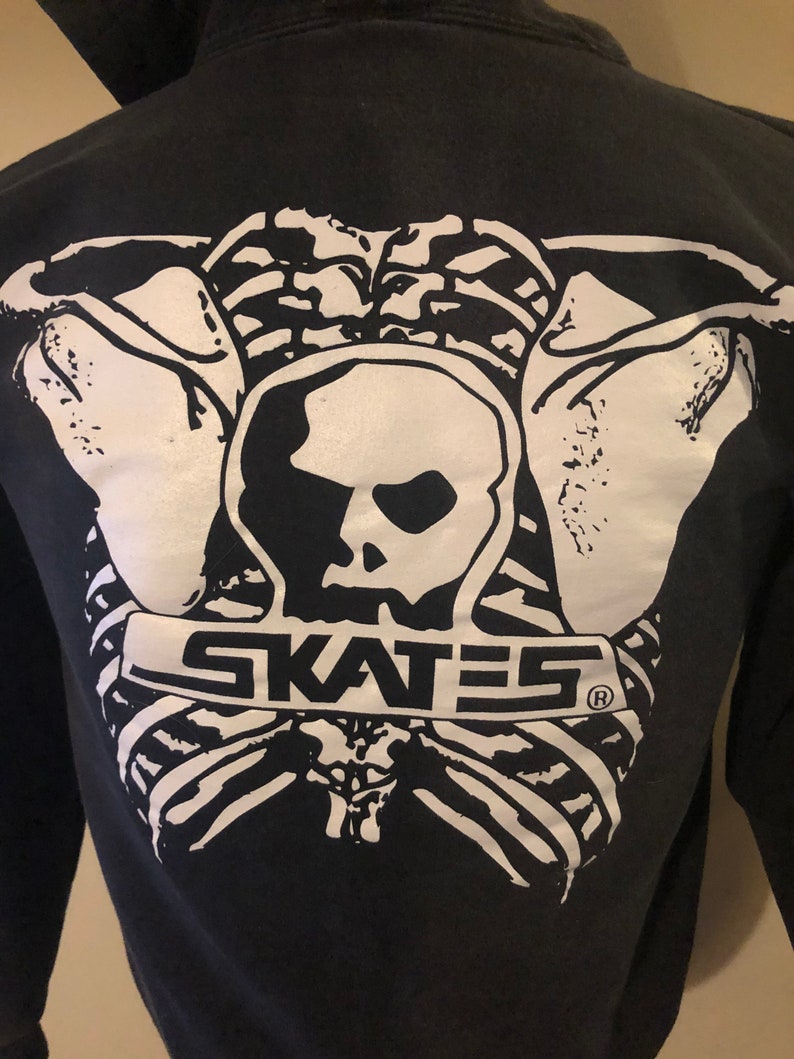 May include: Black hoodie with a white graphic of a skeleton holding a skull with the word "SKATES" printed below.
