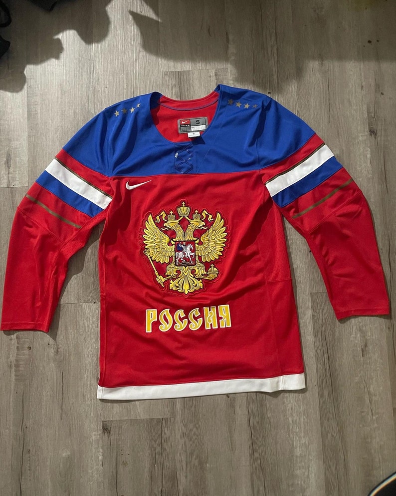 May include: Red, white, and blue hockey jersey with the Russian coat of arms and the word "Россия" on the front. The jersey has a Nike logo on the sleeve.