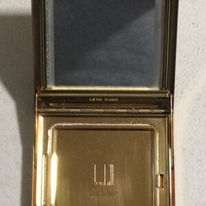 May include: A gold compact with a mirror and a 'L.L.L. Classic' inscription.