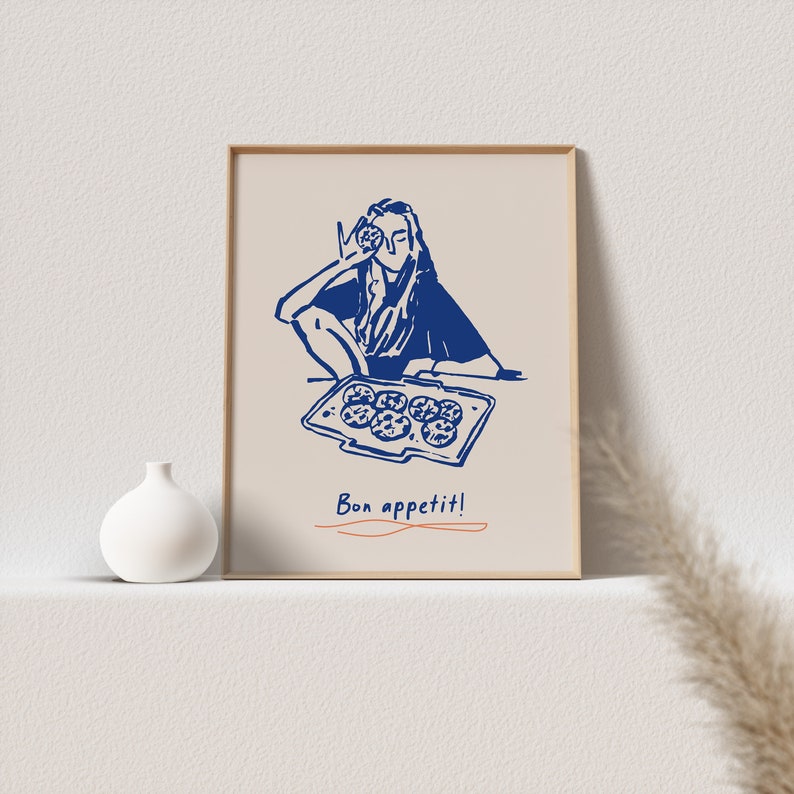 May include: A blue and white illustration of a person holding a cookie and sitting at a table with a tray of cookies. The text "Bon appetit!" is written below the image.