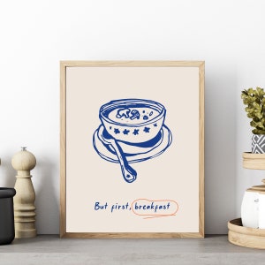 May include: A blue and white illustration of a bowl of cereal with a spoon on a plate. The text "But first, breakfast" is written below the bowl.
