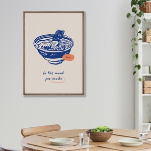 May include: A framed illustration of a bowl of ramen noodles with the text "Ramen" and "In the mood for noodles" in a blue and orange color scheme.