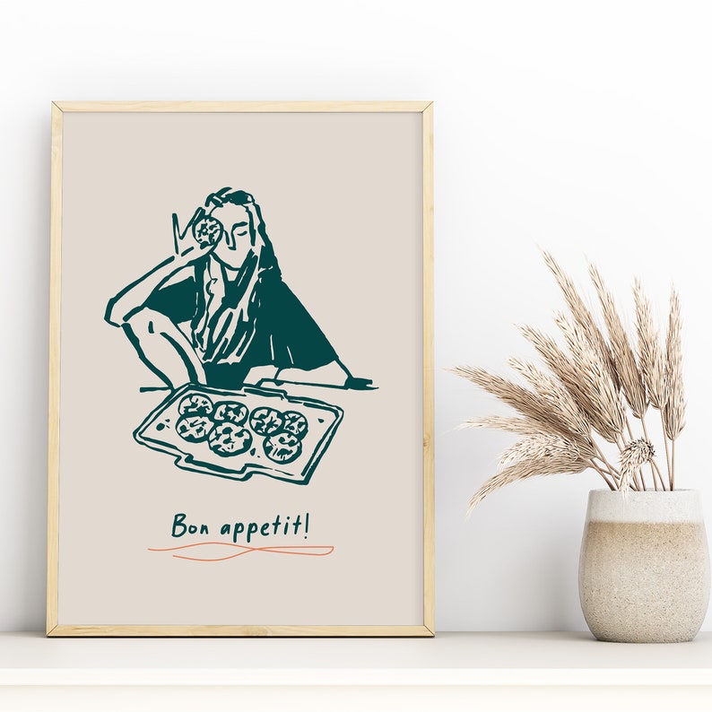 May include: A framed illustration of a person holding a cookie and a tray of cookies with the text "Bon appetit!" in a teal color.