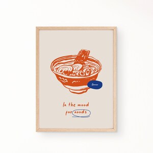 May include: A framed print with a hand-drawn illustration of a bowl of ramen noodles. The text "In the mood for noodles" is written below the bowl.