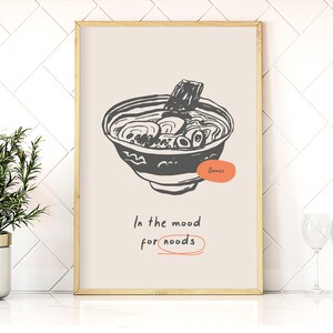 May include: A beige poster with a black and white illustration of a bowl of ramen noodles. The text "In the mood for noodles" is written below the illustration.