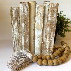 May include: A stack of vintage books with distressed white paint, a wooden bead garland, and a white and brown tassel.