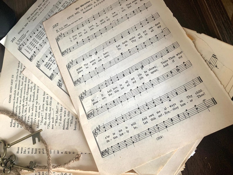 May include: A close-up of a stack of vintage sheet music with the title "Give Me, O Lord, A Shelter" and the lyrics "Let faith make all my conduct, Thy will be all my law." The music is printed in black ink on white paper.