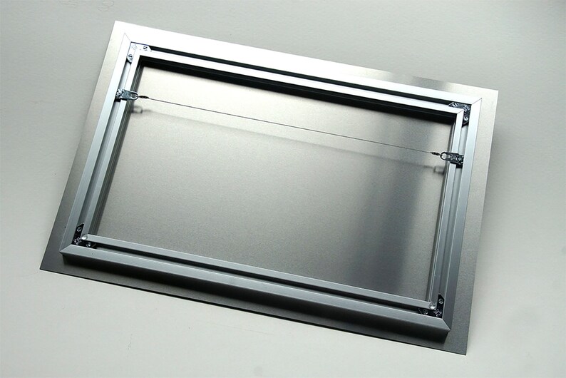 May include: A rectangular metal print with a silver frame and a wire hanging system. The back of the print is a brushed silver color. The frame is made of aluminum and has a black border.