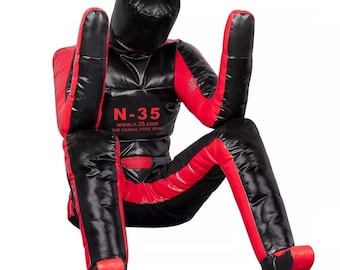 Puede incluir: Un maniquí de entrenamiento negro y rojo para artes marciales. El maniquí está sentado con los brazos y las piernas extendidos. El texto "N-35" y "www.n.35.com THE CASUAL FIGHT GEAR" es visible en el pecho.