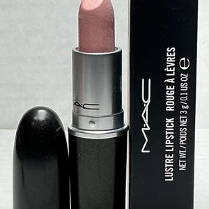 May include: A light pink lipstick with a silver tube and a black cap. The lipstick is next to a black box with the text "LUSTRE LIPSTICK ROUGE À LÈVRES NET WT./POIDS NET 3 g/0.1 US OZ e" and the brand logo.
