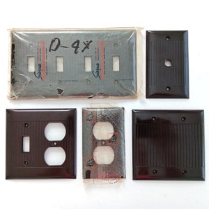 Könnte beinhalten: Ein Satz von vier Vintage-Steckdosen- und Lichtschalterabdeckungen aus braunem Kunststoff. Die Abdeckungen haben eine gerippte Textur und sind mit "Sierra" beschriftet.