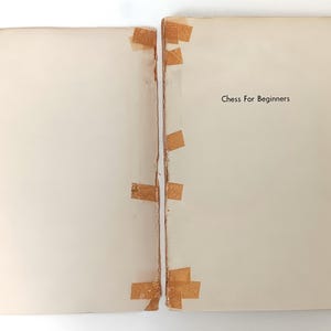 May include: A white book with the title "Chess For Beginners" printed on the cover. The book is taped together with brown tape.