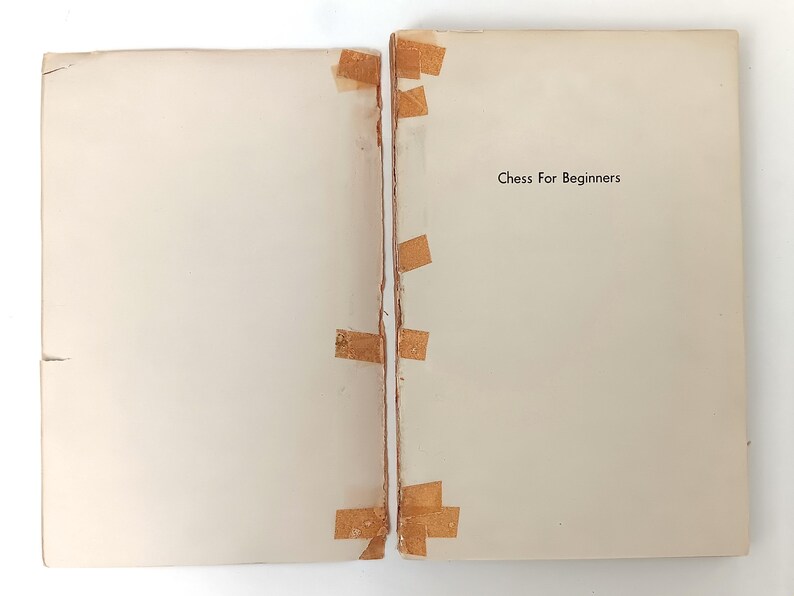 May include: A white book with the title "Chess For Beginners" printed on the cover. The book is taped together with brown tape.