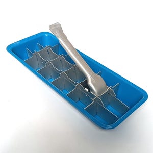 May include: A blue ice cube tray with metal dividers and a stainless steel ice tongs. The tray is rectangular and has a series of compartments for making ice cubes. The tongs are resting on top of the tray.