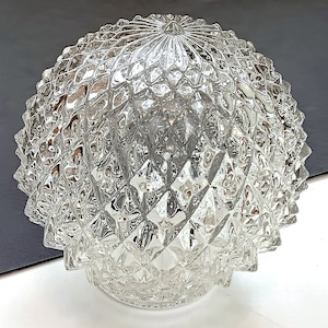 May include: A clear glass light fixture globe featuring a textured diamond pattern across its spherical surface. The glass has a faceted, geometric design that creates a repeating grid of raised points, converging at the top centre of the dome.