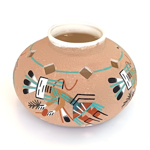Puede incluir: Una maceta de cerámica de color terracota con diseños recortados. La maceta está decorada con patrones geométricos turquesa, negro y blanco y figuras estilizadas.