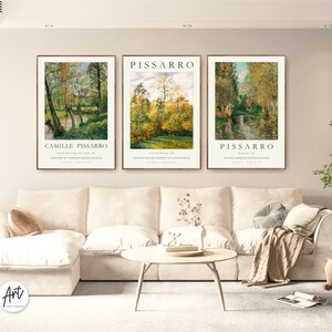 May include: Three framed art prints of landscape paintings by Camille Pissarro. The prints are in a living room setting with a white couch and a coffee table.