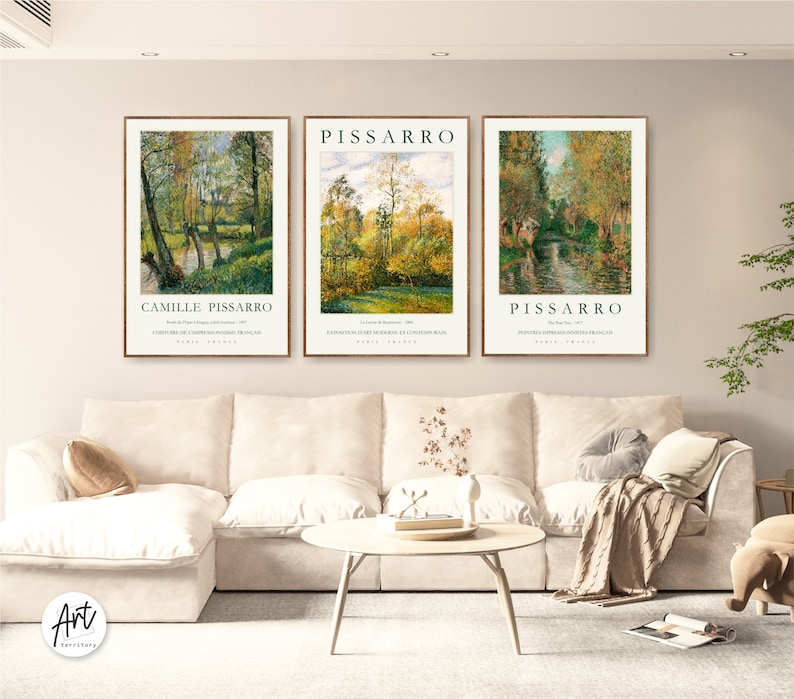 May include: Three framed art prints of landscape paintings by Camille Pissarro. The prints are in a living room setting with a white couch and a coffee table.