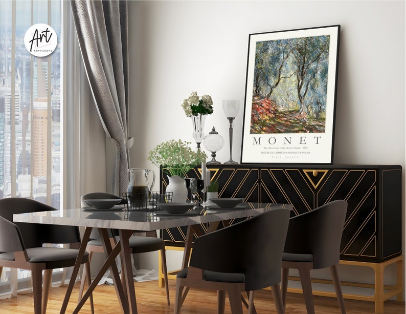 Op de afbeelding: Een zwart en gouden dressoir met een geometrisch patroon en een ingelijste print van een schilderij van Claude Monet met de titel "De olijfgaard in het domein van Saint-Clair, 1884". De print toont een landschapssc&egrave;ne met olijfbomen en een pad.