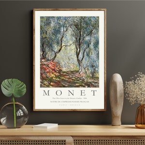 Op de afbeelding: Een ingelijste print van een schilderij van Claude Monet met de titel "The Olive Grove in the Montross Garden - 1884". Het schilderij toont een olijfgaard met een pad dat er doorheen loopt. De bomen zijn geschilderd in tinten groen en blauw, met hints van geel en oranje. De tekst "MONET" is in grote letters onder het schilderij gedrukt, samen met de titel en de informatie over de kunstenaar.