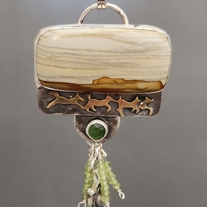 May include: A silver and gold pendant with a beige and brown agate stone, a green gemstone, and green beads hanging from the bottom.