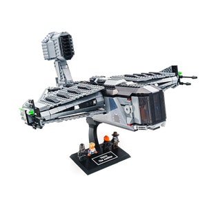 Puede incluir: Una nave espacial Lego Star Wars The Justifier gris y negro con tres minifiguras. La nave espacial tiene una gran cabina y un cuerpo largo y delgado. Las minifiguras están de pie sobre una base negra.