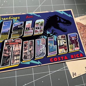 以下が含まれることがあります： 「Greetings from Isla Nublar Costa Rica」と太字で書かれたヴィンテージスタイルのポストカード。恐竜のシルエットと文字の中の画像が特徴です。コスタリカの地図が描かれた2枚目のポストカードも写っています。