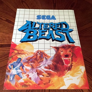 May include: A Sega Mega Drive video game cartridge box featuring a colourful illustration of a werewolf, a man, and a woman in a forest setting. The title of the game, "ALTERED BEAST", is displayed in blue letters on a white background.