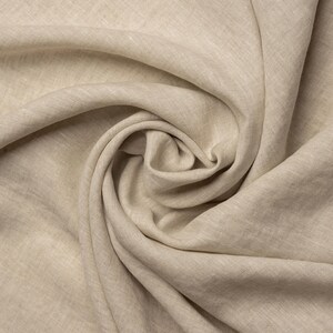 Pu&ograve; includere: Un primo piano di un tessuto di lino beige, che mostra la sua texture naturale e il suo morbido drappeggio.