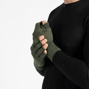 Puede incluir: Guantes sin dedos de color verde oliva. Los guantes están hechos de un material de punto y tienen aberturas para los dedos y el pulgar. Los guantes están diseñados para mantener las manos calientes y permitir la destreza.