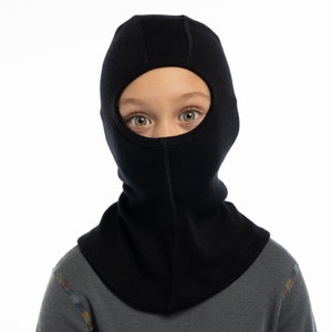 May include: A black fleece balaclava with a hole for the eyes. The balaclava is worn by a child.