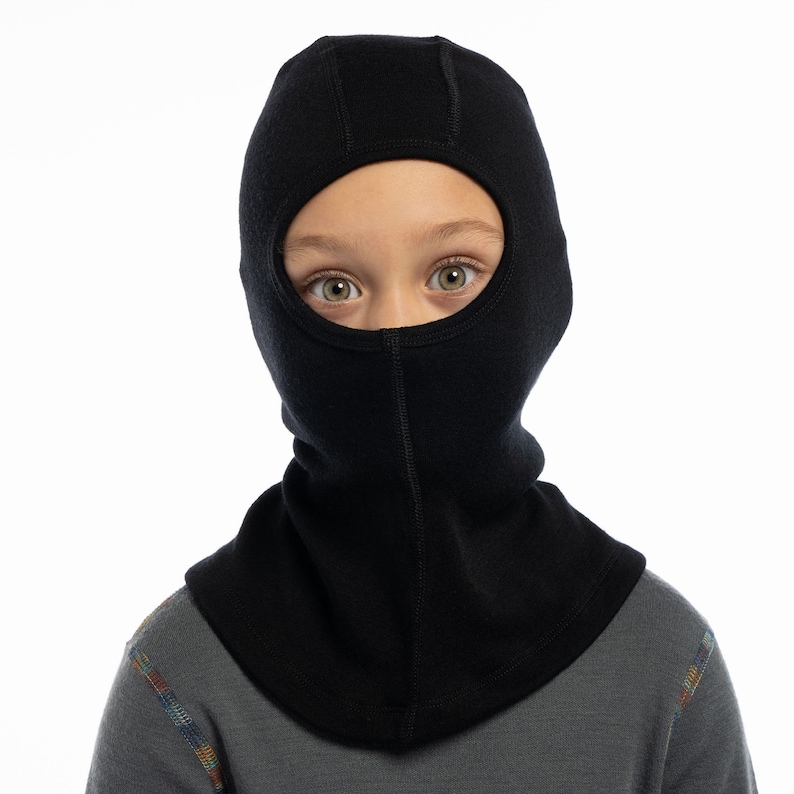 May include: A black fleece balaclava with a hole for the eyes. The balaclava is worn by a child.