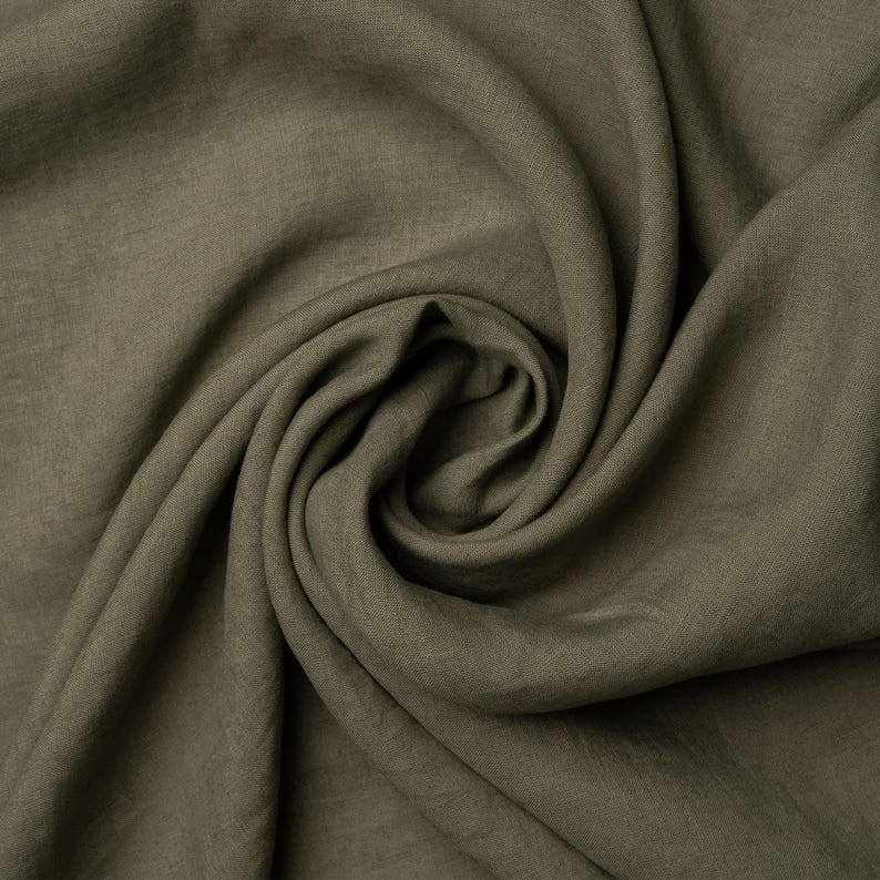 Pu&ograve; includere: Primo piano di un tessuto morbido di colore verde con una texture stropicciata. Il tessuto &egrave; piegato e drappeggiato, creando una curva liscia e fluida.