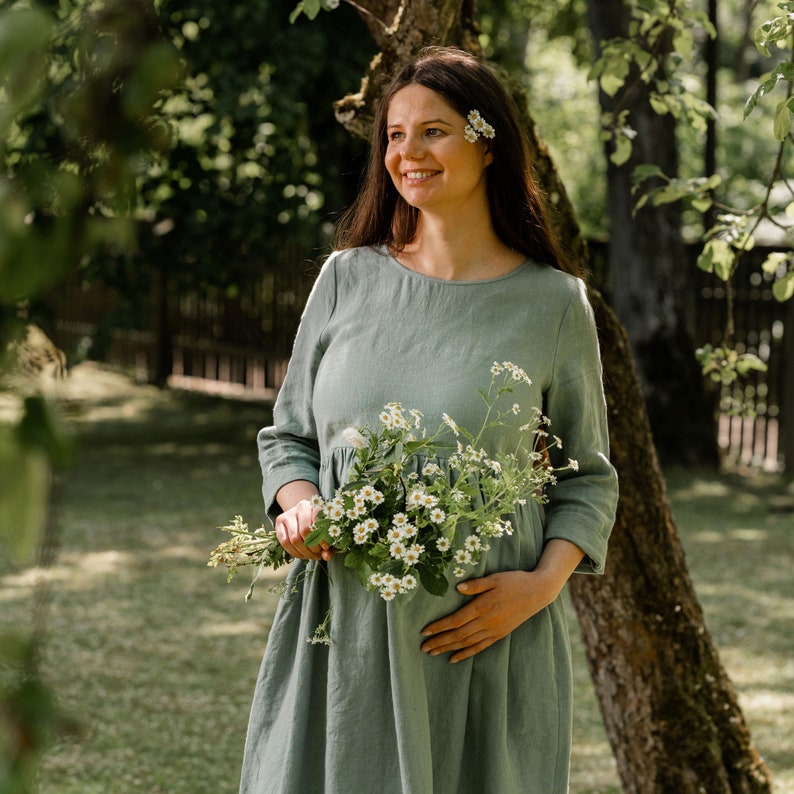 In the photograph the model is wearing the maternity dress LUCY in mint green color. The round neckline compliments the neck.