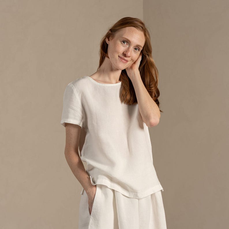 The model wears the EMMA linen t-shirt blouse in pure white