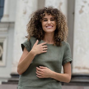 The model wears the EMMA linen t-shirt blouse in stone green