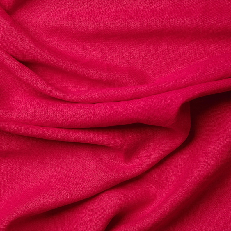 May include: A close-up of a smooth, red fabric with a soft, wrinkled texture.