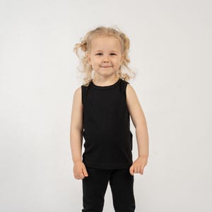 May include: A solid black sleeveless tank top paired with matching black pants. The tank top features a simple crew neckline and a clean, unadorned design. The outfit consists of two separate pieces in a uniform black color, providing a basic look.