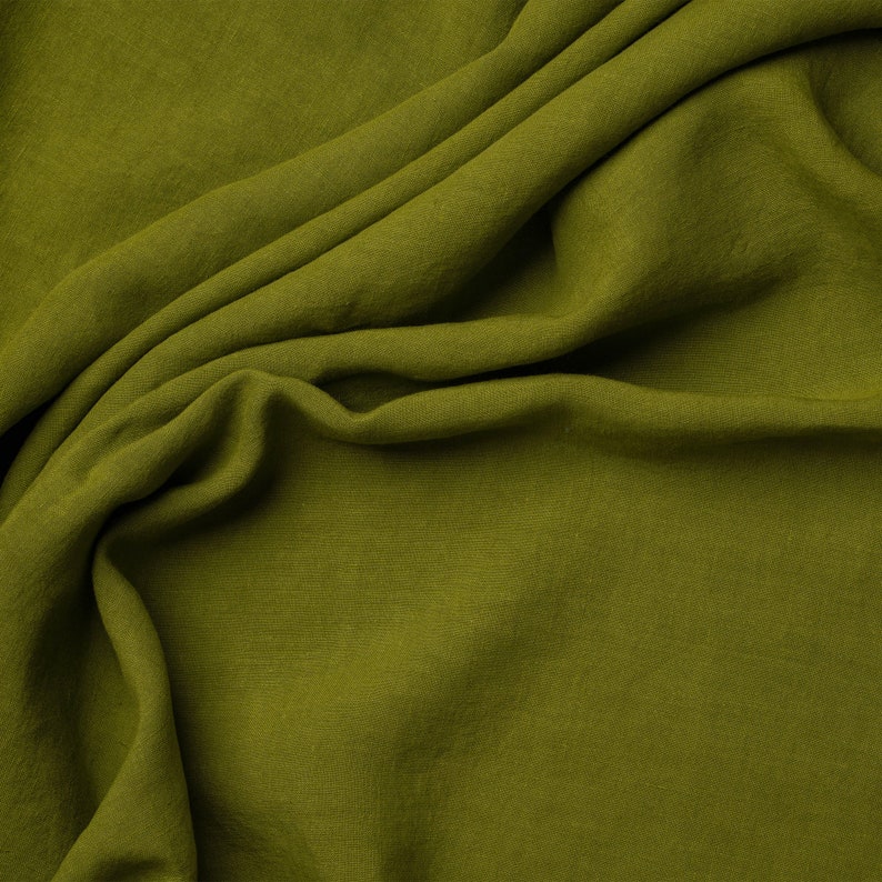 May include: A close-up of a soft, green fabric with a wrinkled texture. The fabric is folded and draped, creating a smooth, flowing surface.