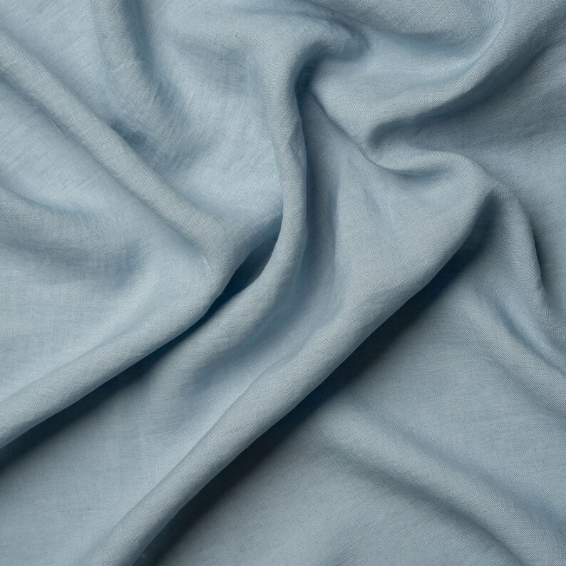 May include: A close-up of a light blue linen fabric with a soft, wrinkled texture.