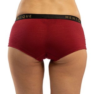 May include: Red underwear with a black waistband and the words "UNIQUE" and "MENIQ" printed in gold.