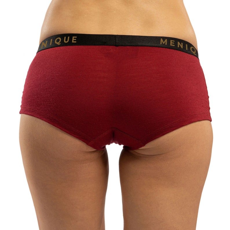 May include: Red underwear with a black waistband and the words "UNIQUE" and "MENIQ" printed in gold.