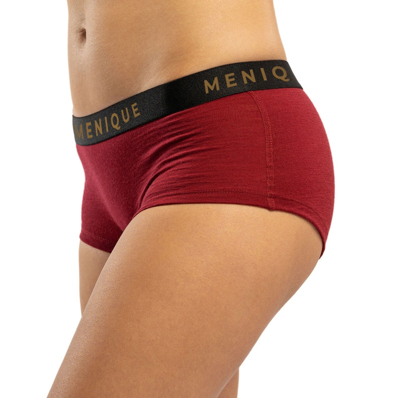 May include: Red underwear with a black waistband that says "MENIQUE" in gold lettering.