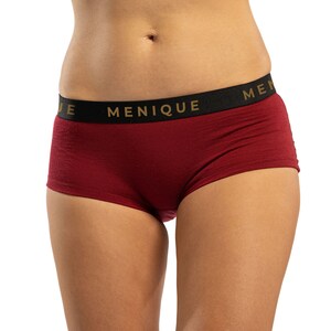 May include: Burgundy red underwear with a black waistband and gold lettering that reads "MENIQUE".